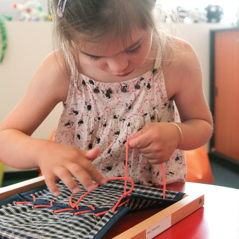 Une enfant entraîne sa motricité avec des lacets