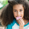 Une petite fille mâchouille un collier de mastication