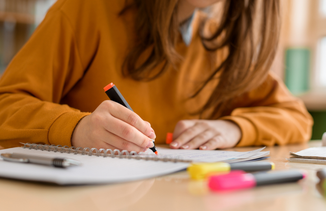 Une adolescente surligne sur un cahier