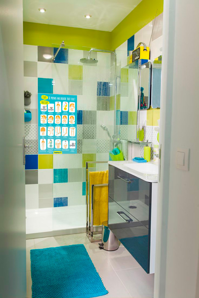 Une salle de bain avec l'infographie "Je me douche tout seul" affichée dans la douche