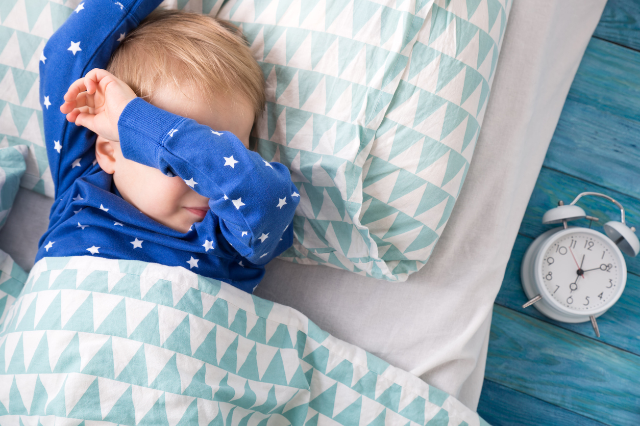 Un enfant avec un pyjama étoilé dort dans un lit