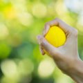 Une main tient une balle anti-stress jaune