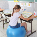 Une enfant assise sur un ballon d'assise dynamique dans une salle de classe