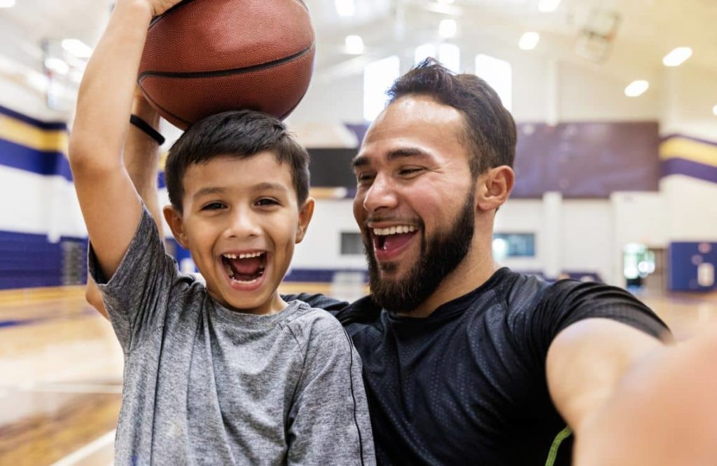Un père et son fils prennent un selfie sur un terrain de basket