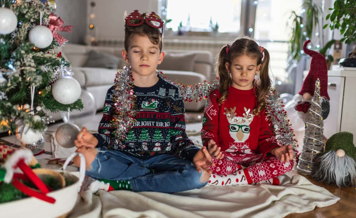 Deux enfants sont assis en tailleur et portent des pulls de Noël