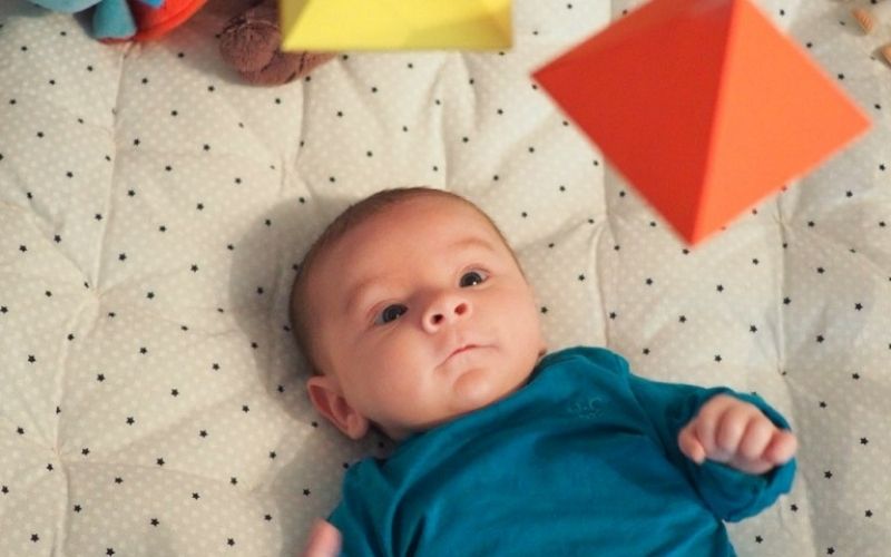 Un bébé allongé regarde un mobile Montessori