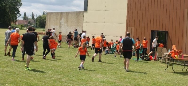Des enfants avec des maillots orange courent dans l'herbe