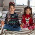 Deux enfants assis en tailleur devant un décor de Noël