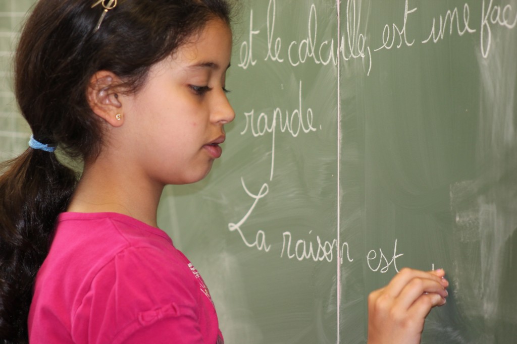 Une jeune fille écrit au tableau