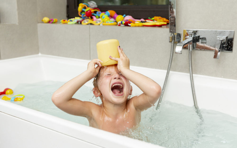 Une fille se renverse un seau d'eau sur la tête dans son bain