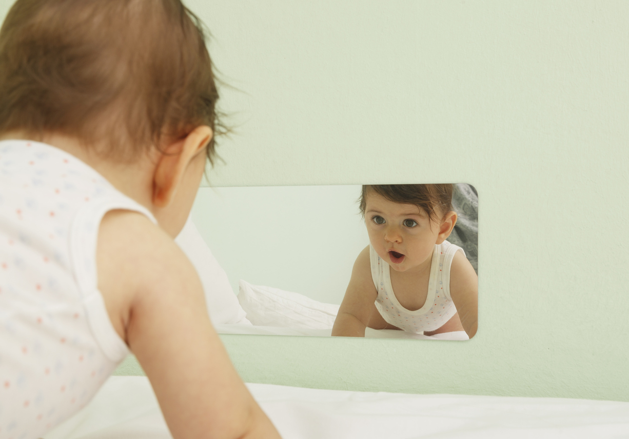 Un bébé se regarde dans un miroir