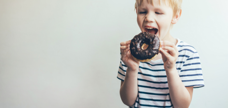 Un enfant mange un donut au chocolat