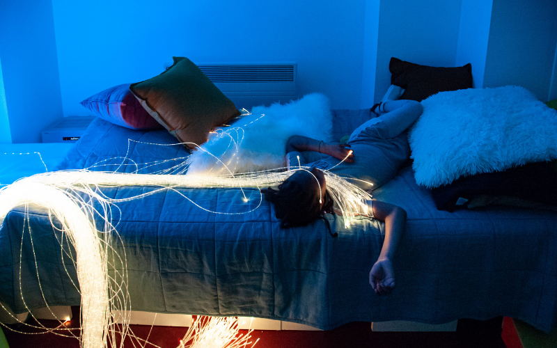 Un enfant est allongé sur un lit avec des fibres optiques