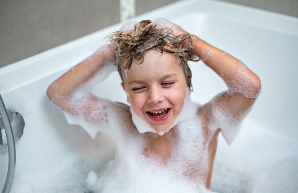 Un enfant se lave les cheveux dans une baignoire