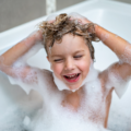 Un enfant se lave les cheveux dans une baignoire