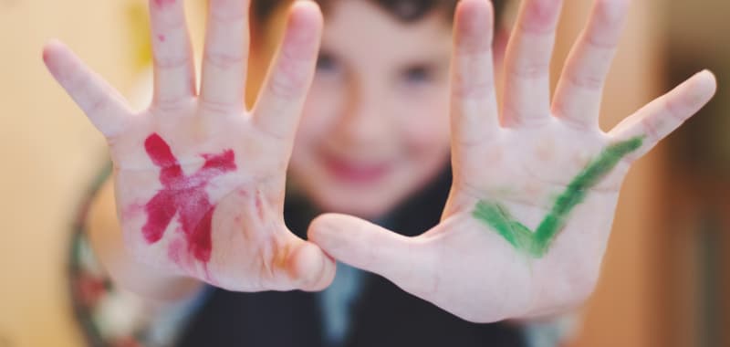 Un enfant avec une croix rouge et un check vert dessinés sur les mains