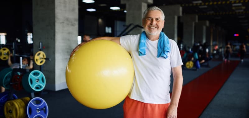 Homme âge s'apprêtant à faire du sport avec une balle sensorielle géante