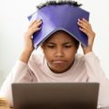 Une enfant avec un cahier sur la tête