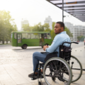 Un homme en fauteuil roulant attend à un arrêt de bus