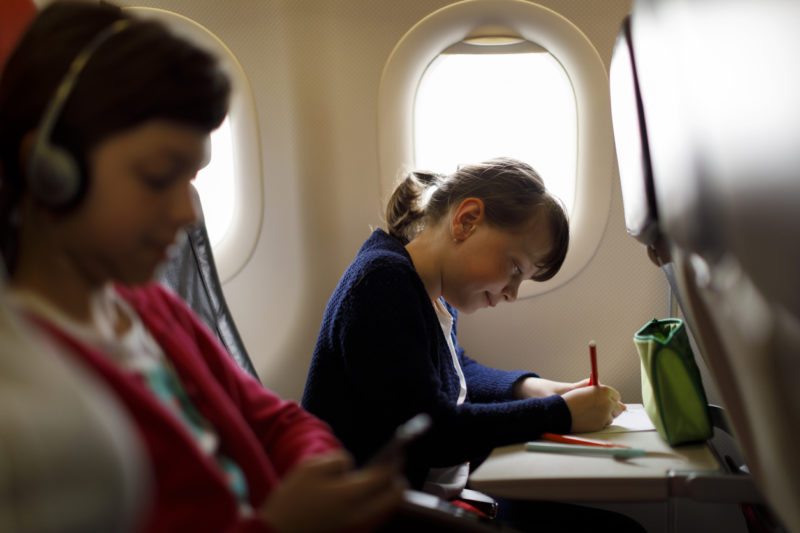 Une enfant dessine dans l'avion