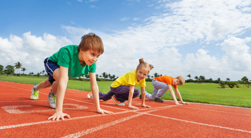 Tres niños en la línea de salida de una pista de atletismo