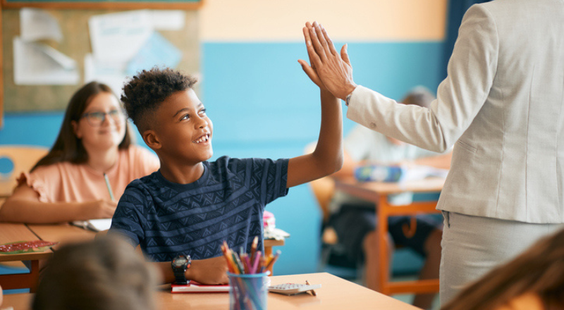 Un enfant tape dans la main de sa professeure