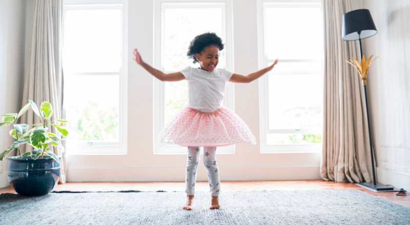 Une petite fille en tutu rose danse dans un salon