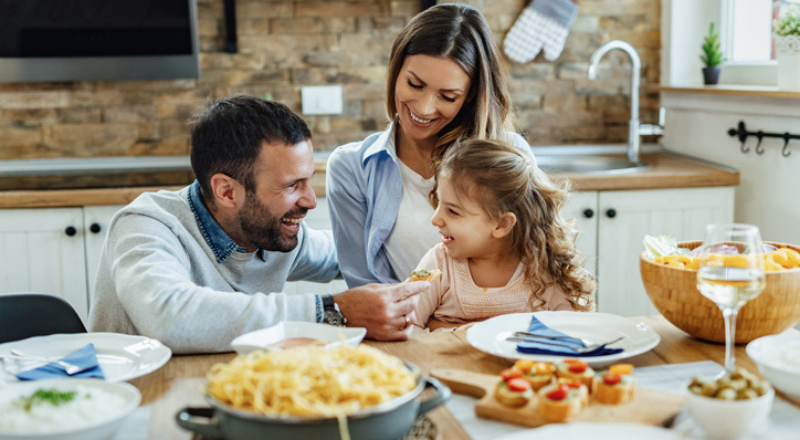 Una familia de tres personas compartiendo una comida en la mesa