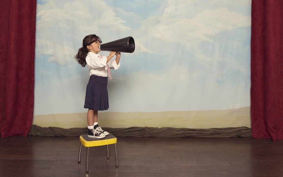 Une petite fille parle dans un mégaphone sur une scène