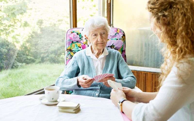 Une personne âgée joue aux cartes avec une personne plus jeune