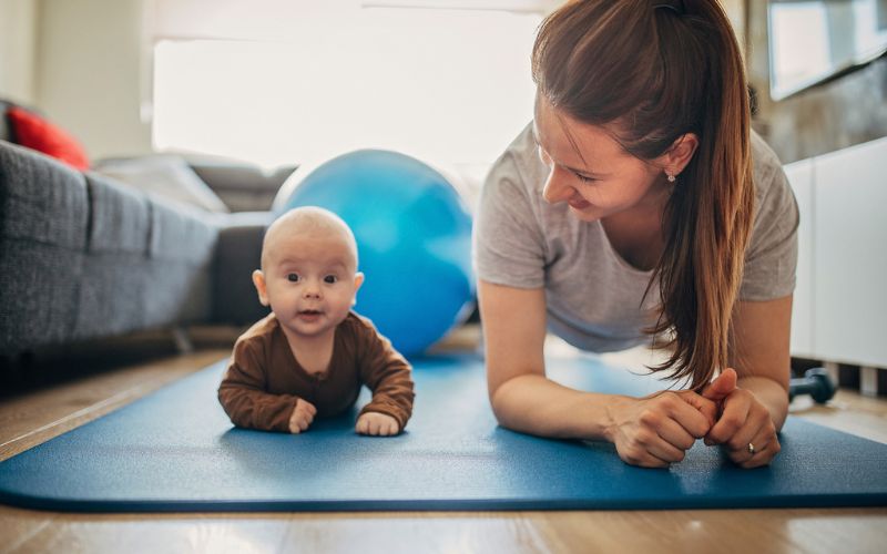 Une mère et son bébé sont allongés sur un tapis de gym