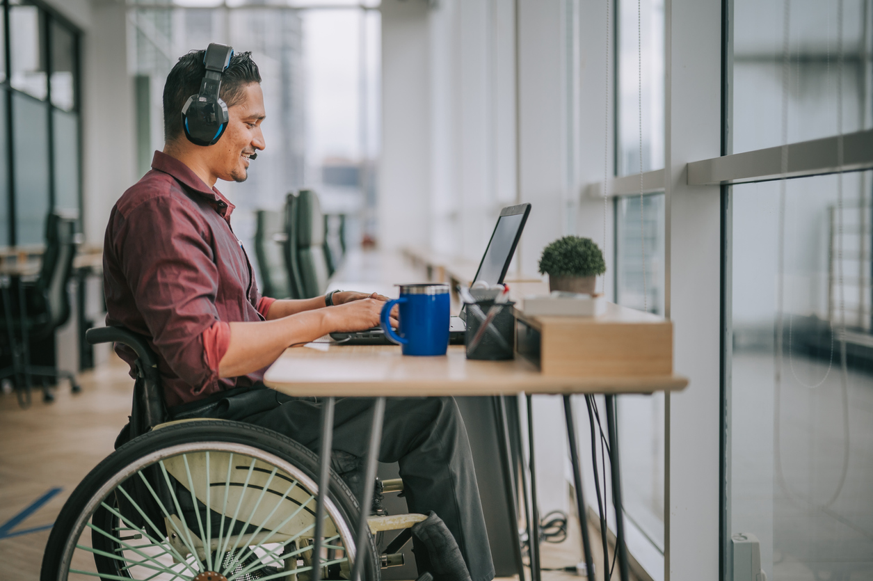 Une personne en fauteuil travaille sur un ordinateur