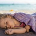 Un enfant fait la sieste sur la plage