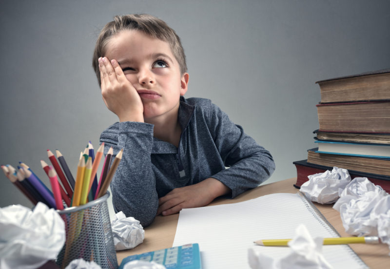 Un enfant s'ennuie devant ses devoirs