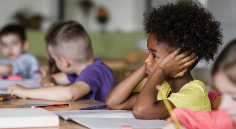 Un enfant se bouche les oreilles dans une salle de classe