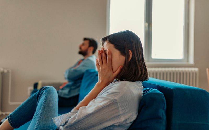 Une femme pleure sur le canapé à côté de son compagnon