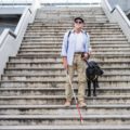 Un homme âgé descend des marches avec une canne blanche