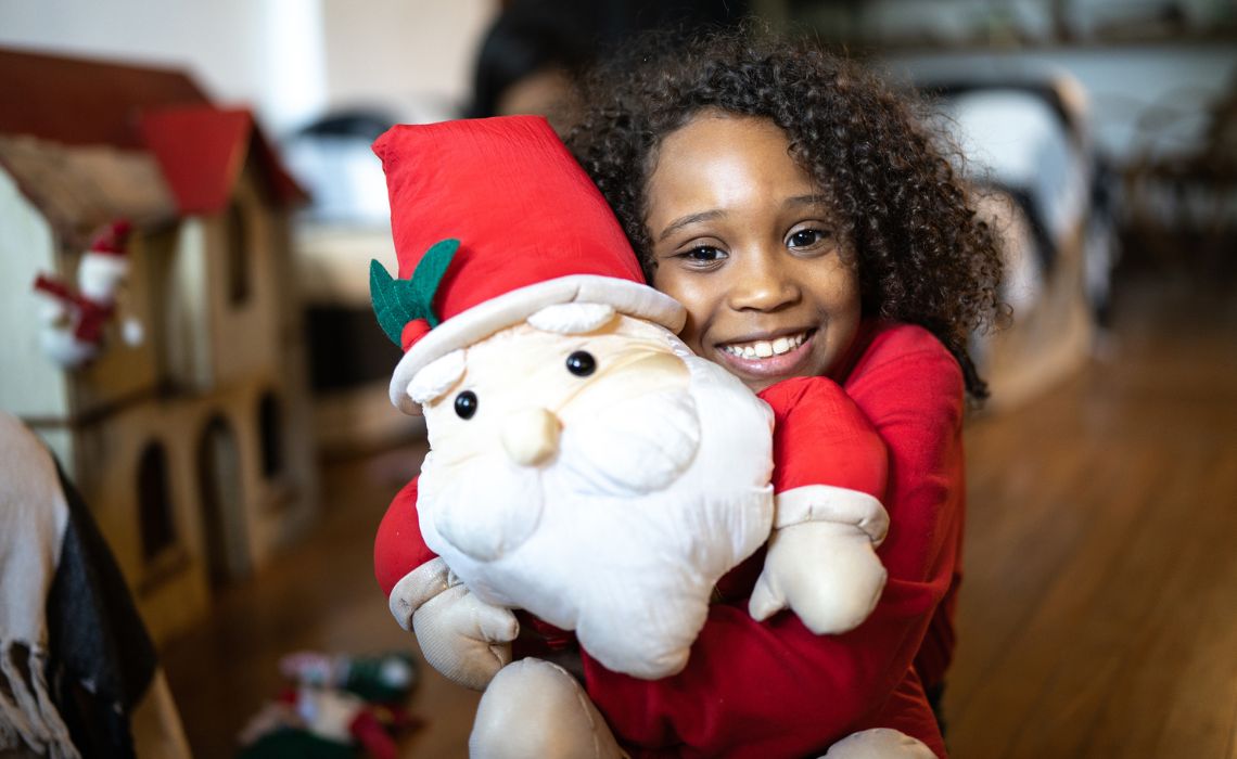 Une petite fille fait un câlin à une peluche du Père Noël