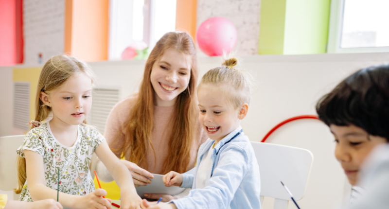 Une enseignante est aux côtés d'enfants qui peignent