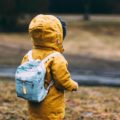 Un enfant avec un ciré jaune et un sac à dos bleu