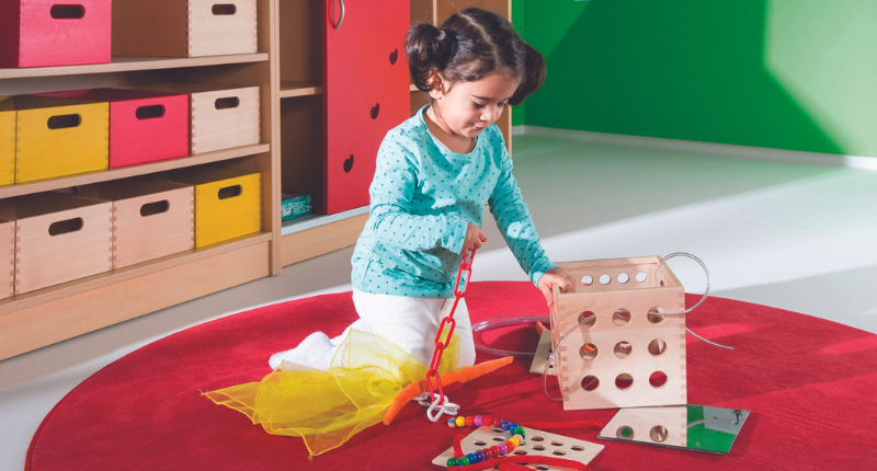 petit fille qui joue avec le Cubetix. Un cube en bois avec différents accessoires;