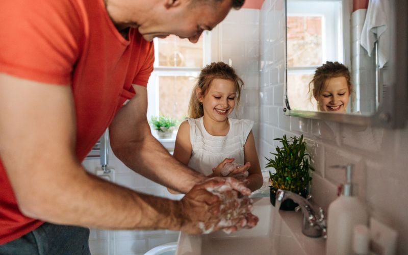 Un père et sa fille se lavent les mains