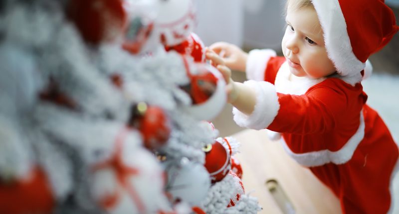 Un enfant déguisé en Père Noël décore un sapin