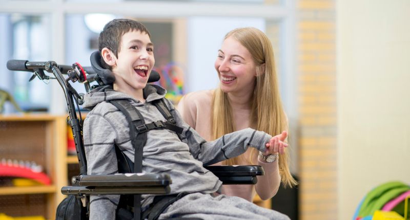 Un enfant dans un fauteuil roulant tient la main d'une femme