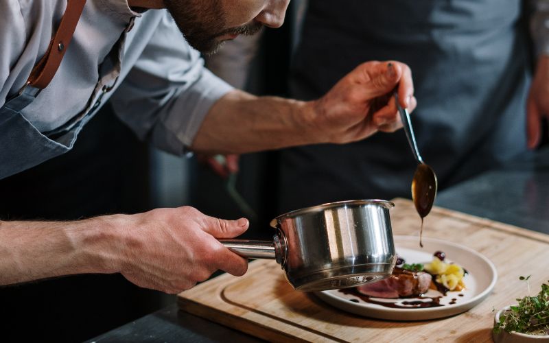 Un cuisinier met de la sauce sur de la viande