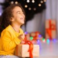 Une petite fille ouvre un cadeau en riant