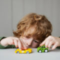 Enfant qui s'ennuie jouant avec deux petites voitures