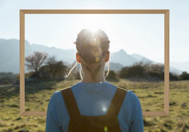 Femme de dos face à un cadre regardant un paysage.