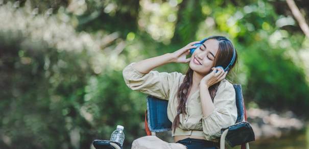 Jeune femme en fauteuil écoutant de la musique dans un casque en pleine nature ou dans un festival
