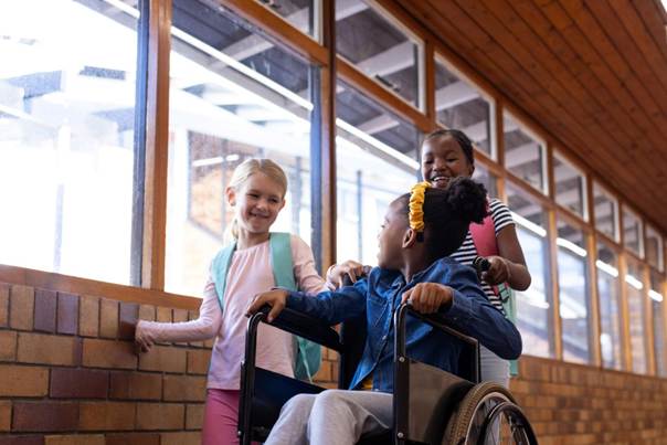 Enfants ensemble et souriant, l'une est en fauteuil roulant
